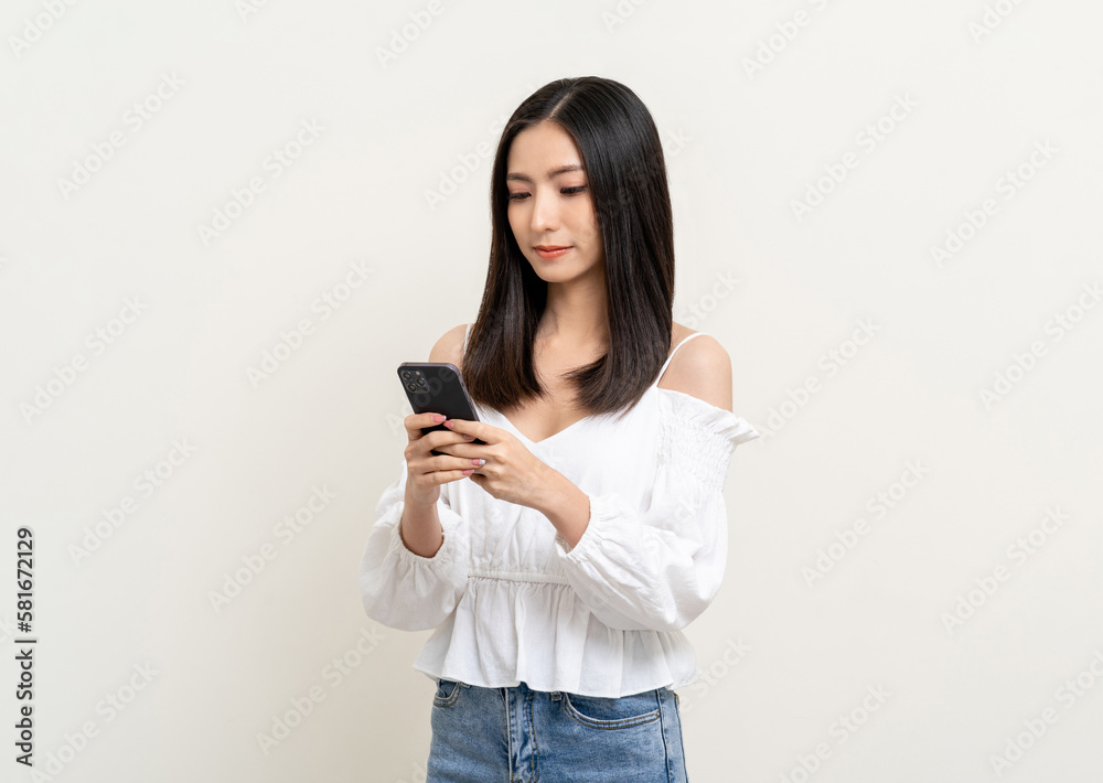 Pretty young asian woman using smartphone standing on isolated white background. Excited Beautiful young asian shopping online payment with mobile phone. Playing game on smartphone Pretty young asian woman using smartphone standing on isolated white background. Excited Beautiful young asian shopping online payment with mobile phone. Playing game on smartphone