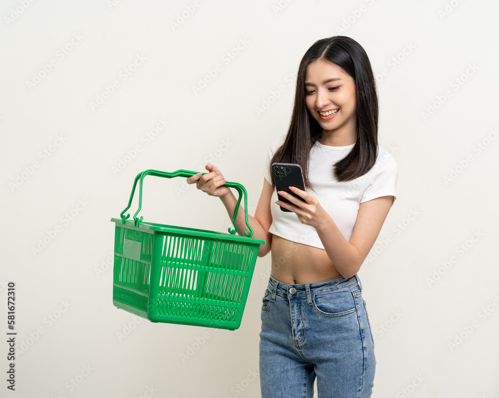 Happy beautiful woman holding shopping basket going to shopping. Using smartphone choose category for shopping online. Application shopping online buy and payment on cell phone. Happy beautiful woman holding shopping basket going to shopping. Using smartphone choose category for shopping online. Application shopping online buy and payment on cell phone.