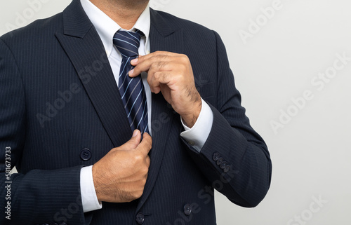 Confident businessman buttoning or adjust classic blue suit on isolated white background. Handsome man wearing a nice suit