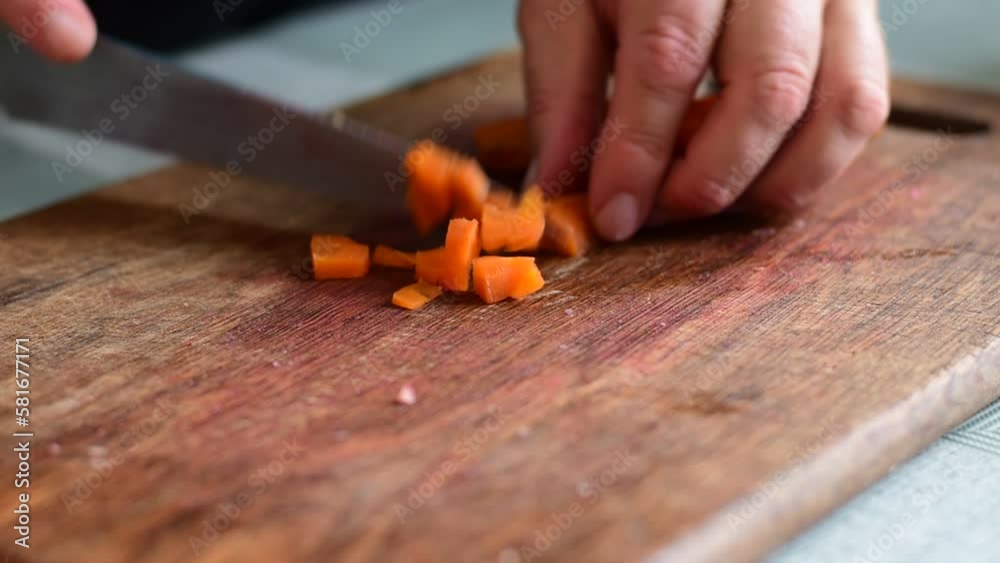 The video shows how male hands, cooks, cut boiled carrots into small pieces with a knife on a cutting board. The video shows how male hands, cooks, cut boiled carrots into small pieces with a knife on a cutting board.