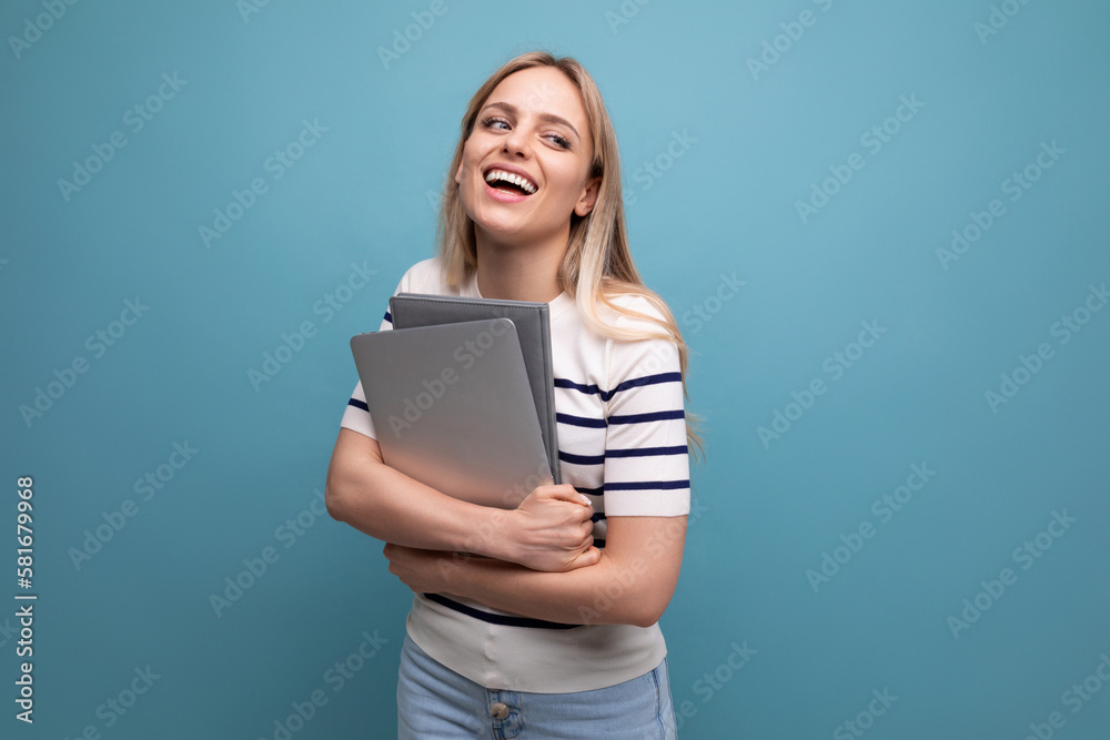 casual confident young female student in casual clothes with laptop on blue isolated background