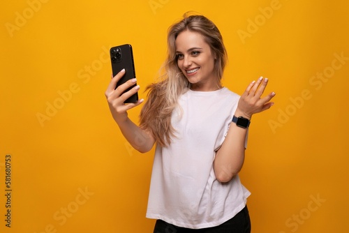 girl takes a selfie on the phone on a yellow background
