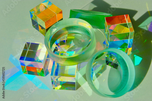 Closeup of convex and concave lens placed on top of dichroic cube prism, dispersing ray of light into spectrum colours, refraction and reflection create colourful shade and shadow on white paper photo