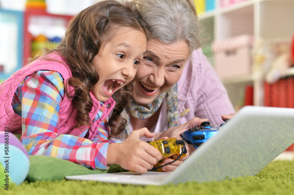 Grandmother with her granddaughter playing computer game Grandmother with her granddaughter playing computer game