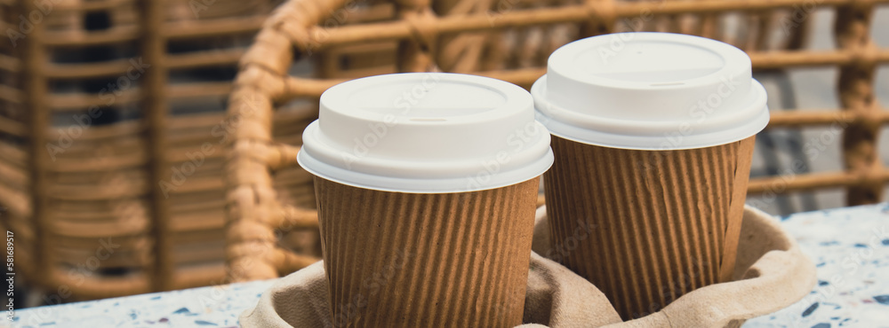 Two paper cups with lid for tea to go. Coffee take away on the table. Take-out coffees with brown paper cup holder. Brown safety cardboard collars. Take away box for cups. Cardboard tray Two paper cups with lid for tea to go. Coffee take away on the table. Take-out coffees with brown paper cup holder. Brown safety cardboard collars. Take away box for cups. Cardboard tray