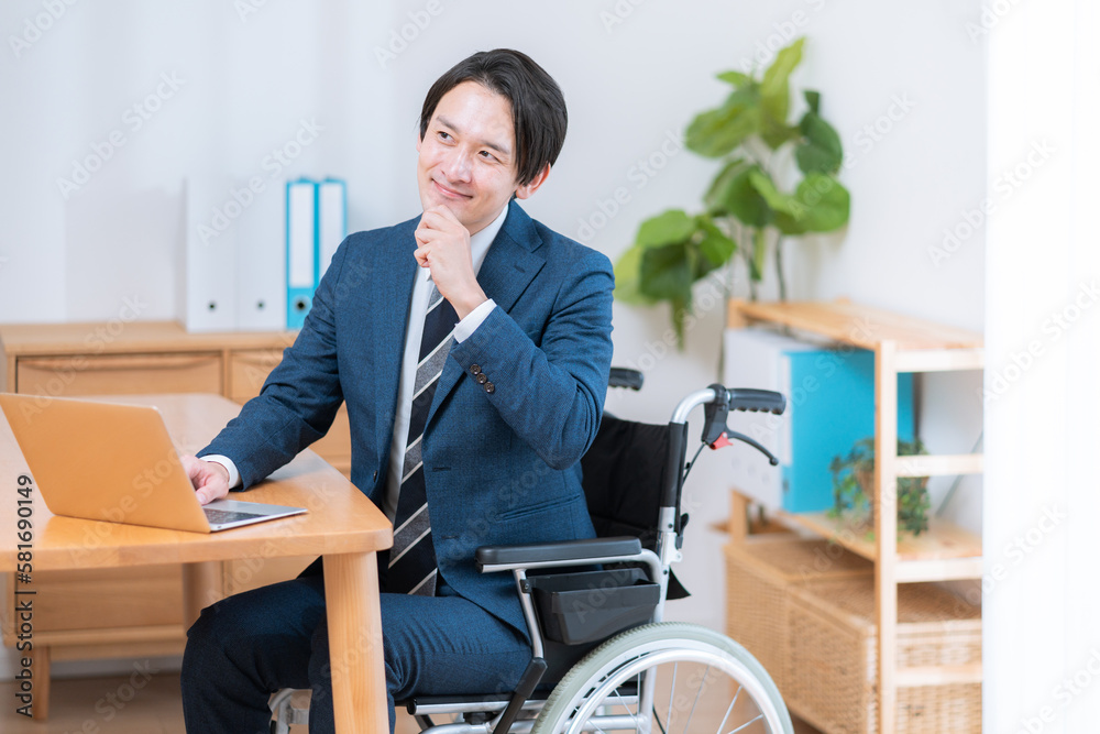 車椅子に座って仕事をするビジネスマン 車椅子に座って仕事をするビジネスマン