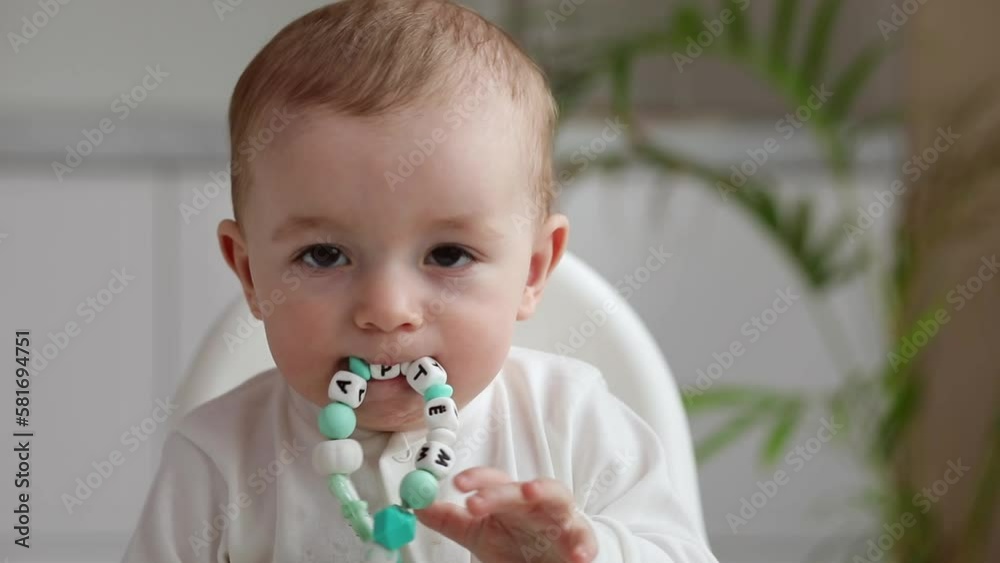 Cute little baby sitting in high chair holding spoon, looking aside smiling, Cute little baby sitting in high chair holding spoon, looking aside smiling,