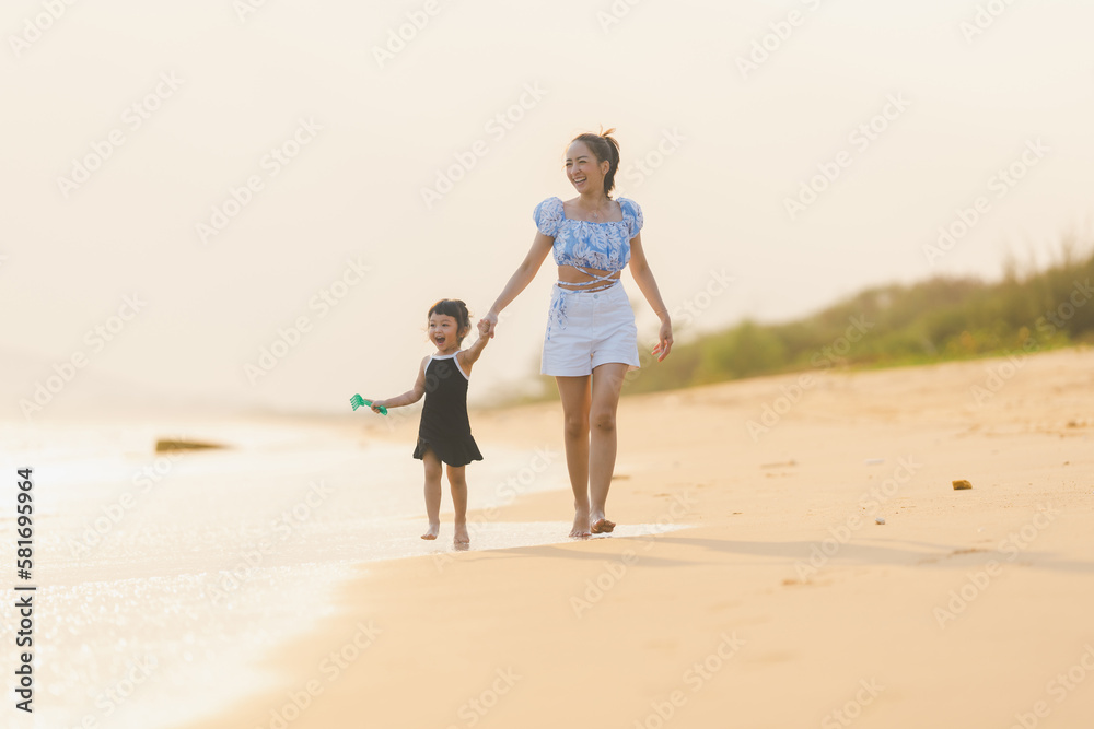happy time of mom and daughter in dress black walking and run play on the beach with blur background beautiful sunset light in the sea