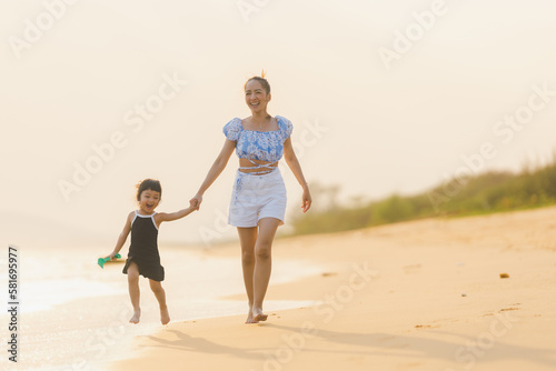 happy time of mom and daughter in dress black walking and run play on the beach with blur background beautiful sunset light in the sea