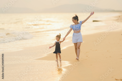 happy time of mom and daughter in dress black walking and run play on the beach with blur background beautiful sunset light in the sea