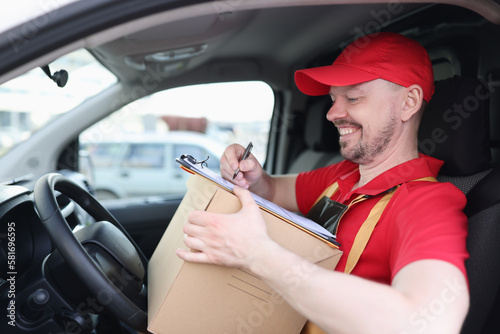 Happy delivery man with cardboard box checklist in van