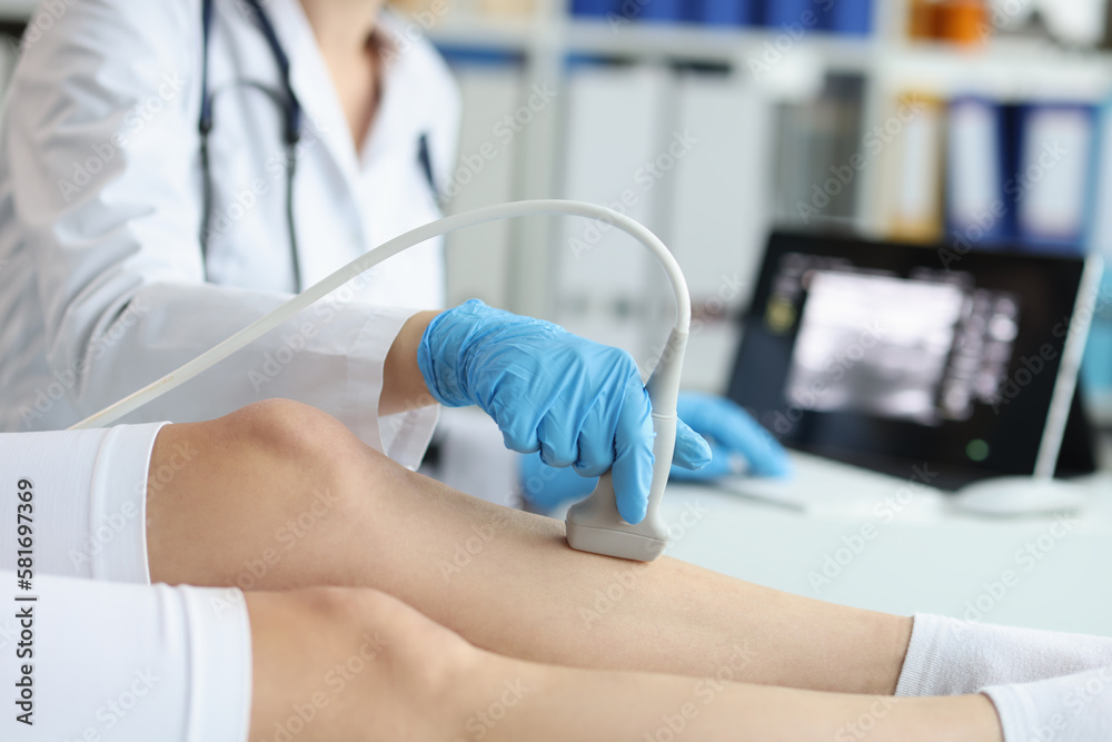 Doctor makes ultrasound scan of knees and legs of woman