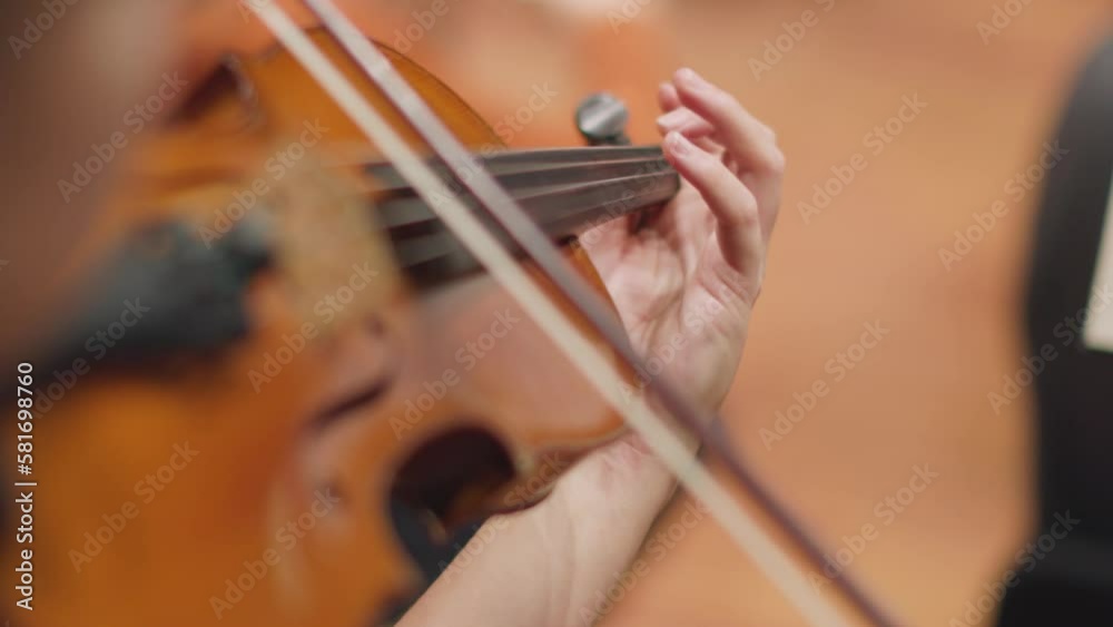 A slow motion video of a musician playing the violin with a bow during a classical symphony orchestra rehearsal A slow motion video of a musician playing the violin with a bow during a classical symphony orchestra rehearsal