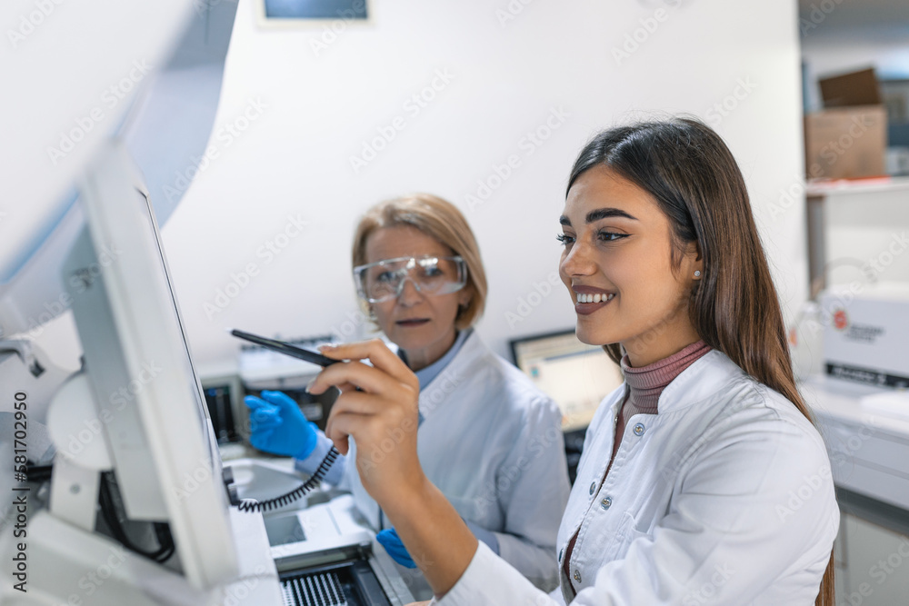 Fototapeta premium Two Research Scientists Programm Medical Equipment with Tablet Computer. Team of Professionals Doing Pharmaceutical Research in Modern Laboratory.