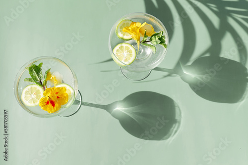 Fotografia Iced lemonade with edible nasturtium flowers, lime and mint leaves