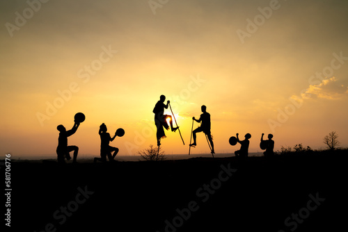 Silhouettes of Ede boys and girls performing their traditional dance during sunset in Pleiku town, Gia Lai province, Vietnam. © Quang