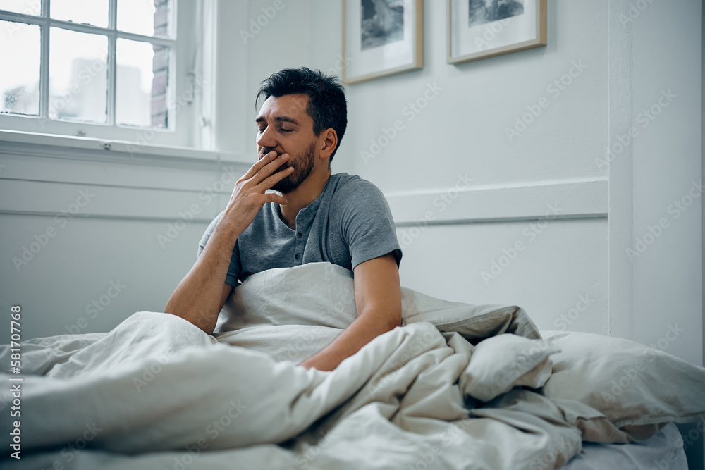 Tired man yawning while waking up at home. Tired man yawning while waking up at home.