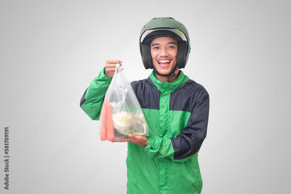Portrait of Asian online taxi driver wearing green jacket and helmet delivering the vegetables from traditional market. Isolated image on white background Portrait of Asian online taxi driver wearing green jacket and helmet delivering the vegetables from traditional market. Isolated image on white background