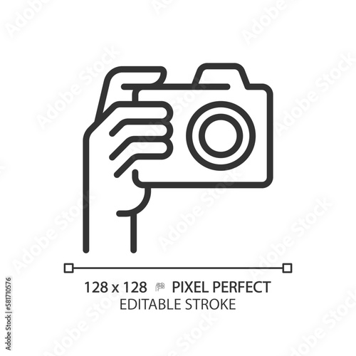 Hand with camera pixel perfect linear icon. Person taking shot with analog equipment. Photographer tool. Thin line illustration. Contour symbol. Vector outline drawing. Editable stroke