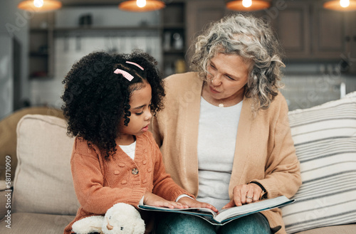 Family kid, book and grandmother reading fantasy storybook, story or bonding on home living room sofa. Love, grandma babysitting and senior woman with child development for adoption kindergarten girl