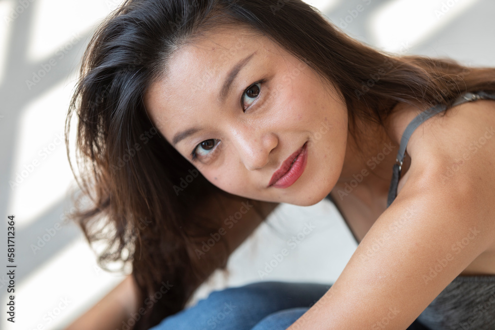 Portrait beautiful Asian girl sitting on the ground. Close up. Behind comes the sunlight.