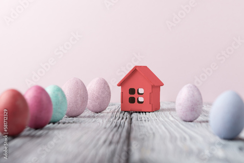 Decorative house and Easter eggs over pinkt background with copy space. Easter holiday greeting concept photo