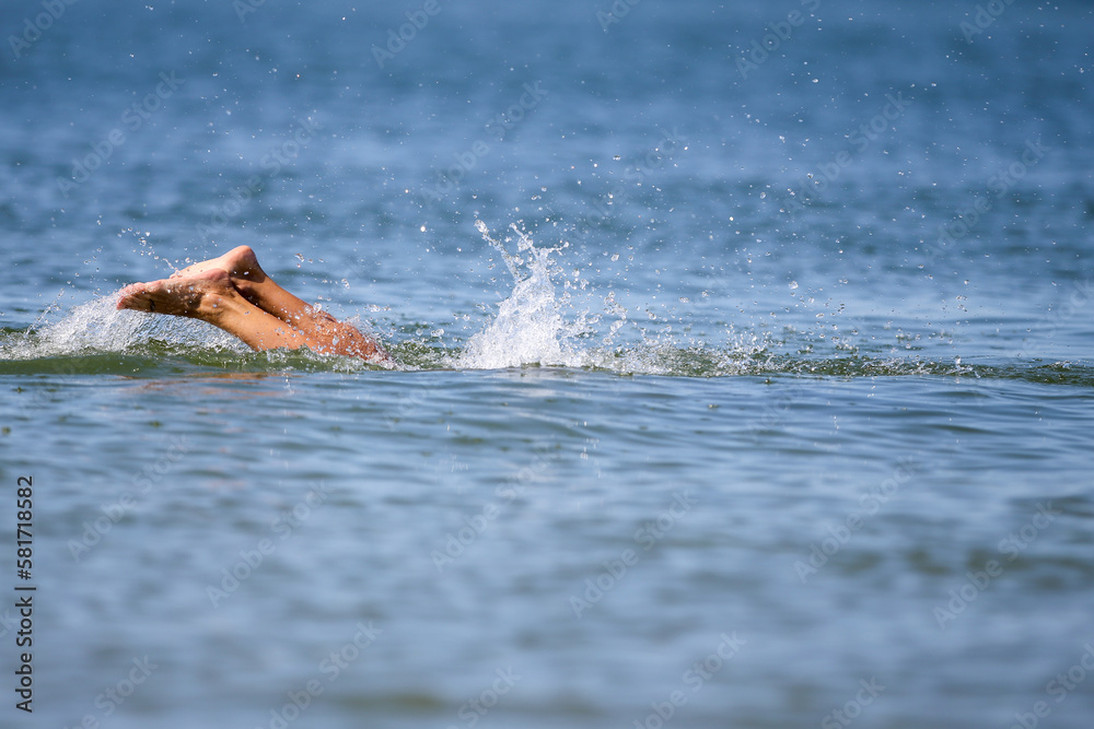 Drowning woman's legs sticking out of sea