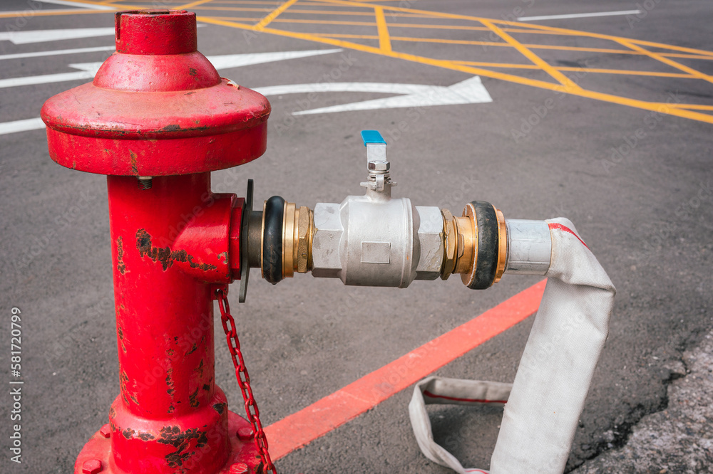 Close up on a fire hose connected to a red water hydrant.