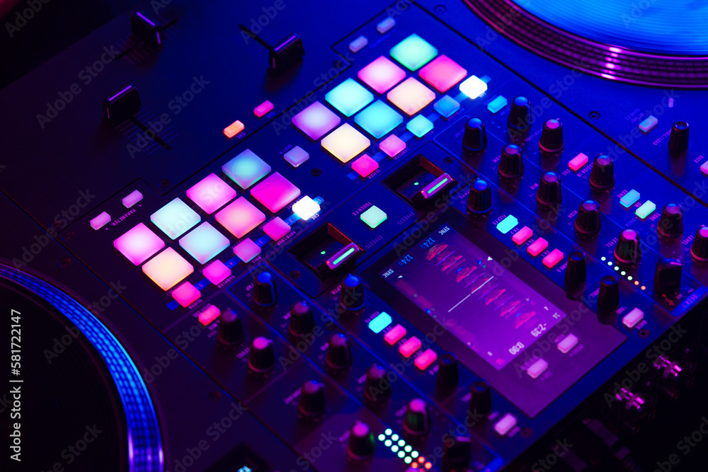 Close up of DJ mixing console in party light