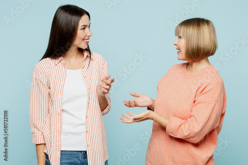 Smiling happy fun elder parent mom with young adult daughter two women together wearing casual clothes talk speak have pleasent conversation isolated on plain blue cyan background. Family day concept. photo
