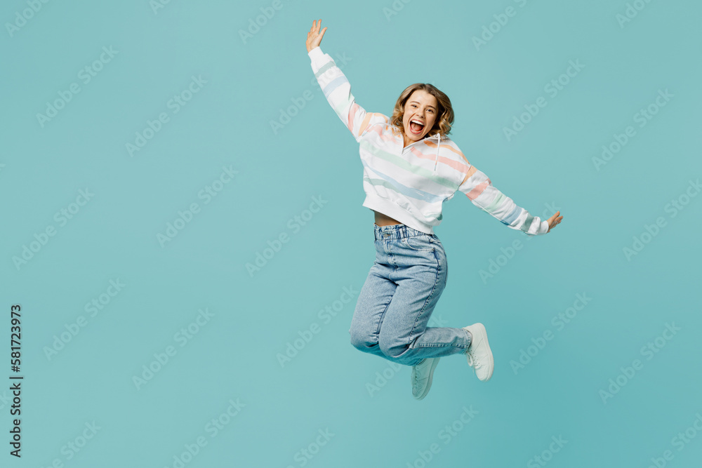 Full body exultant overjoyed excited young woman wear striped hoody jump high with outstretched hands look camera isolated on plain pastel light blue cyan background studio portrait Lifestyle concept Full body exultant overjoyed excited young woman wear striped hoody jump high with outstretched hands look camera isolated on plain pastel light blue cyan background studio portrait Lifestyle concept