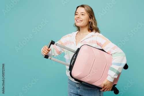 Traveler smiling fun woman wear casual clothes hold suitcase look aside isolated on plain blue cyan background. Tourist travel abroad in free spare time rest getaway. Air flight trip journey concept. #581723966