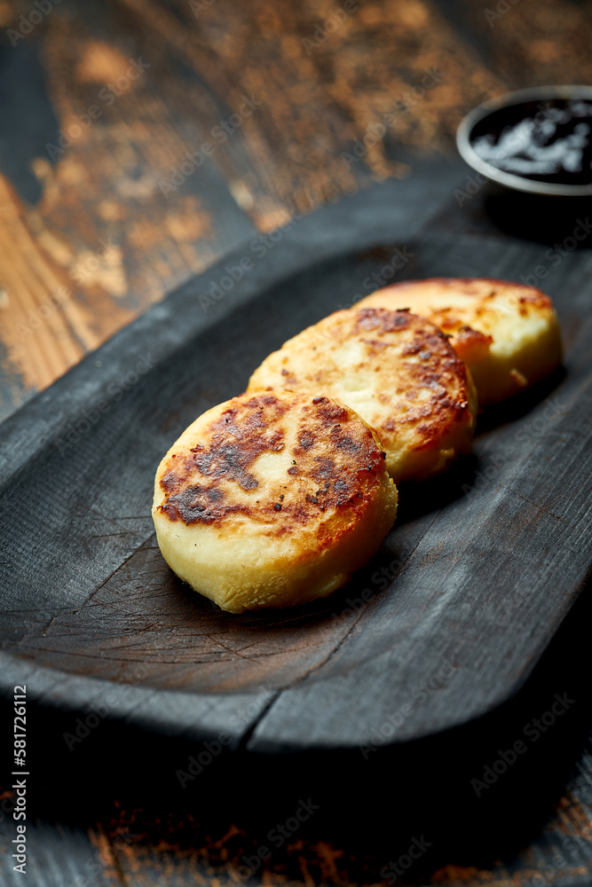 Ukrainian syrnyky on a wooden board on a wooden background, rustic style. fried cheese pancakes Ukrainian syrnyky on a wooden board on a wooden background, rustic style. fried cheese pancakes