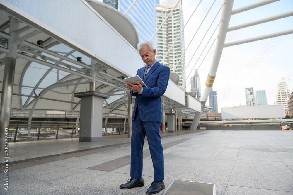 Asian senior mature middle aged businessman using tablet in modern city Asian senior mature middle aged businessman using tablet in modern city