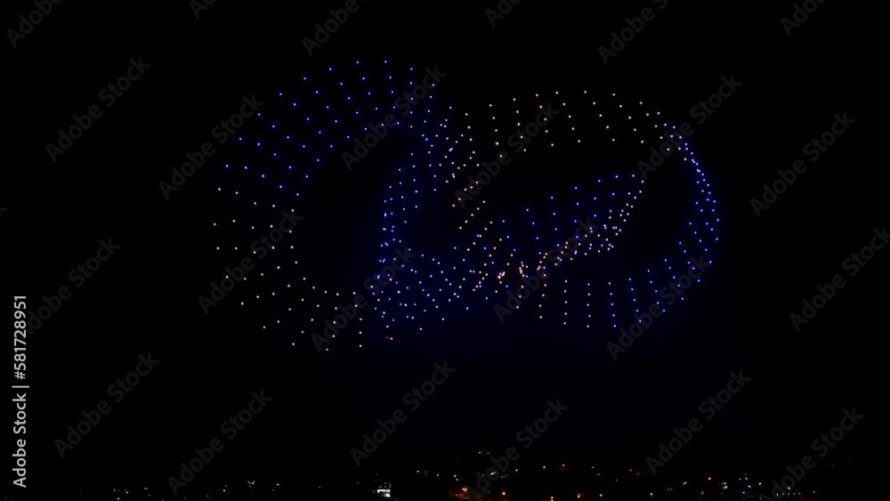 Flying drones creating 3d models moving on night sky over the city lights, exceptional show