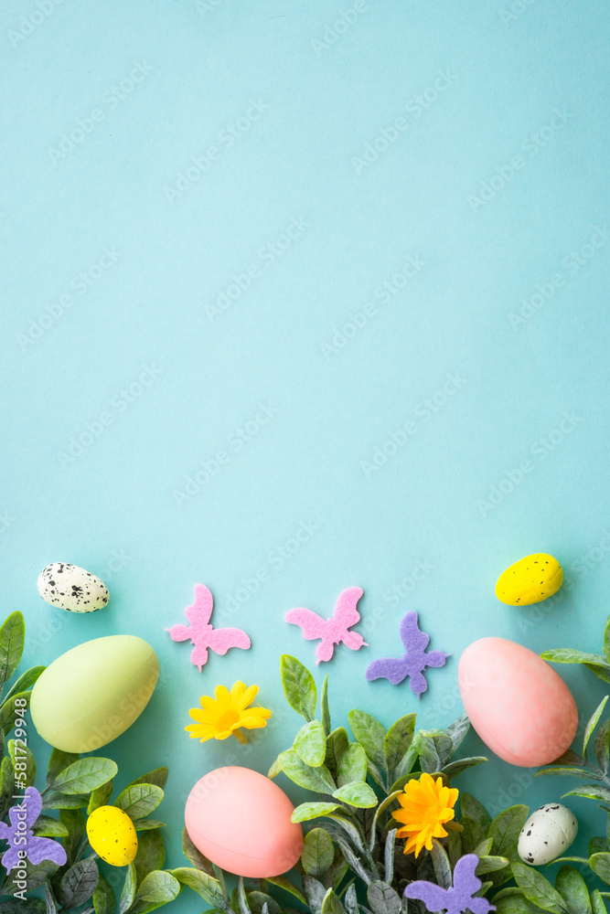 Spring or Easter background on blue. Eggs, spring leaves, flowers and colored butterflies. Flat lay, vertical.