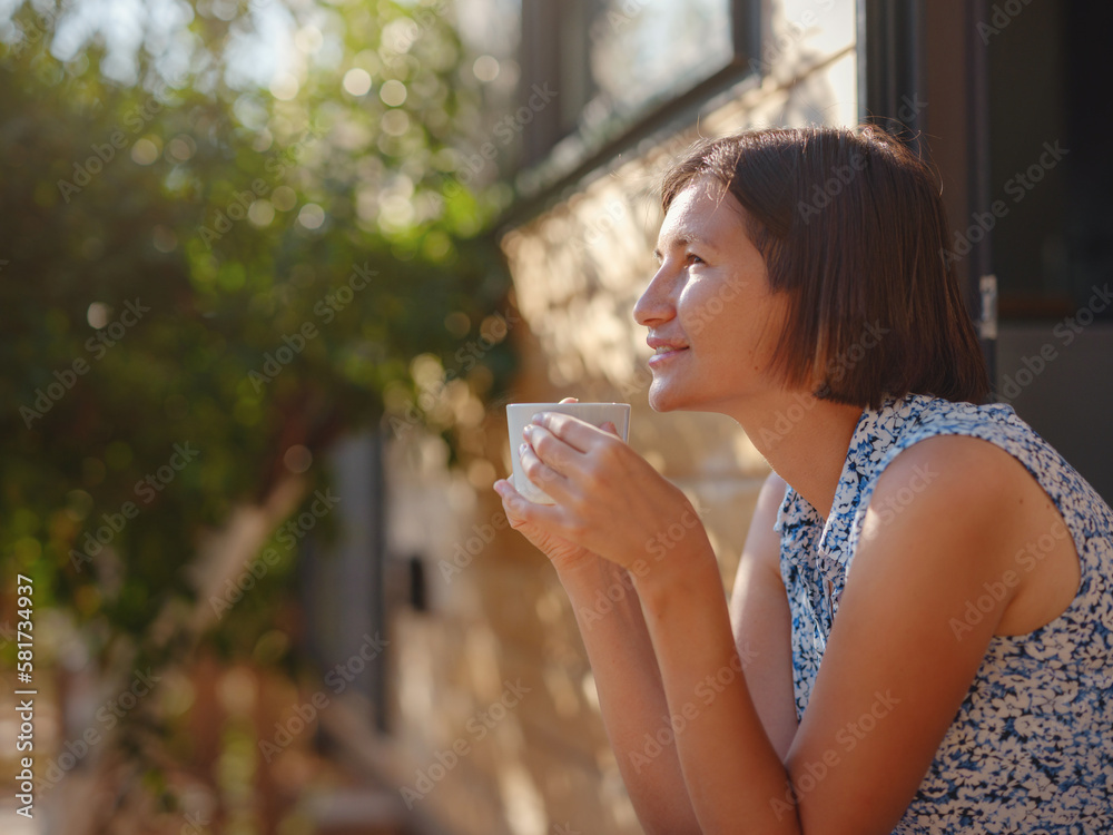 Woman is drinking coffee , morning routine near her Tiny house. First property. Small apartment in summer garden. Minimalism. Moving in. Living alone. Charming trailer house Woman is drinking coffee , morning routine near her Tiny house. First property. Small apartment in summer garden. Minimalism. Moving in. Living alone. Charming trailer house