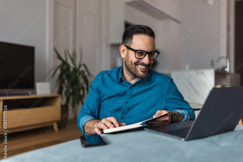 Smiling businessman having an online meeting with colleagues, writing notes in a notebook. Smiling businessman having an online meeting with colleagues, writing notes in a notebook.
