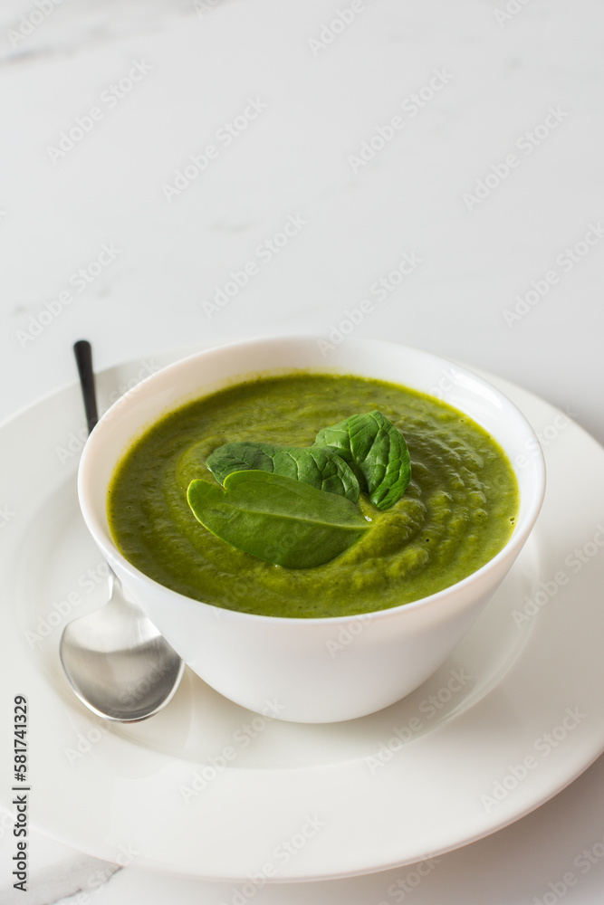 Healthy breakfasts, green broccoli and spinach cream soup in a white bowl on a marble background with a gray napkin, top view Healthy breakfasts, green broccoli and spinach cream soup in a white bowl on a marble background with a gray napkin, top view