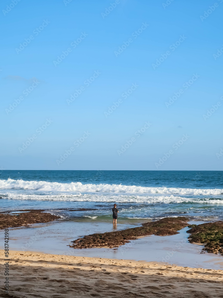 Photo of a woman standing alone at Beach during the day. Girl standing at sandy beach while sunny day. Photo of a woman standing alone at Beach during the day. Girl standing at sandy beach while sunny day.