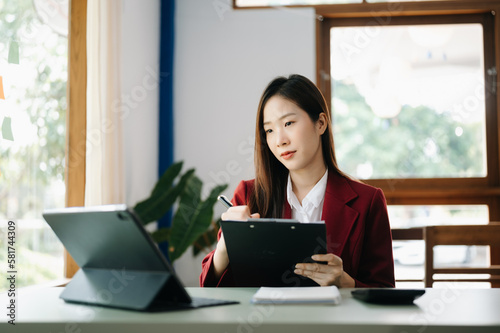 Free Download  Beautiful Asian business woman typing laptop and tablet Placed at the table at the office.. - GFXLoad
