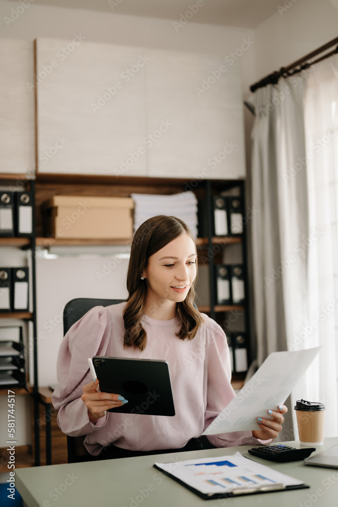 Beautiful business woman typing laptop and tablet Placed at the table at the modern office Beautiful business woman typing laptop and tablet Placed at the table at the modern office