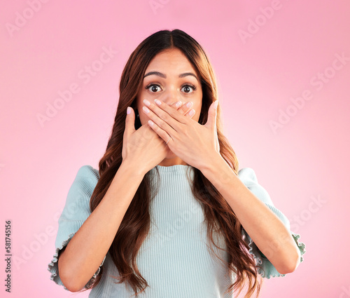Portrait, surprise and woman cover mouth, gossip and scared girl against pink studio background. Face, female and lady with hands on lips, shocked and wow with worry, scary and reaction with bad news