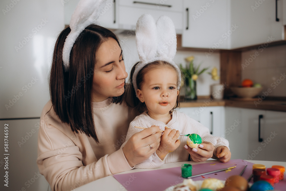 Happy easter. A mother and her daughter painting Easter eggs. Happy family preparing for Easter. Cute little child girl wearing bunny ears on Easter day. Happy easter. A mother and her daughter painting Easter eggs. Happy family preparing for Easter. Cute little child girl wearing bunny ears on Easter day.