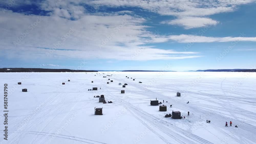An aerial view of ice fishing huts on a frozen lake on a beautiful winter day in Northern Ontario. An aerial view of ice fishing huts on a frozen lake on a beautiful winter day in Northern Ontario.