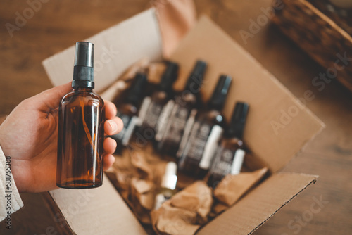 A hand with a jar of oil against the background of a box with funds  unpacking the parcel