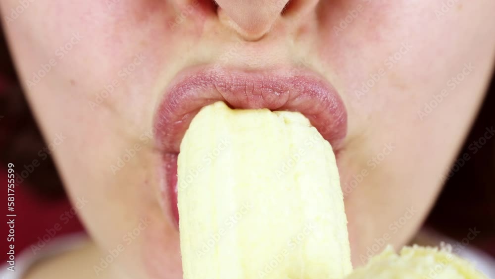 Hungry young woman biting and chewing a fresh yellow banana fruit close up Hungry young woman biting and chewing a fresh yellow banana fruit close up