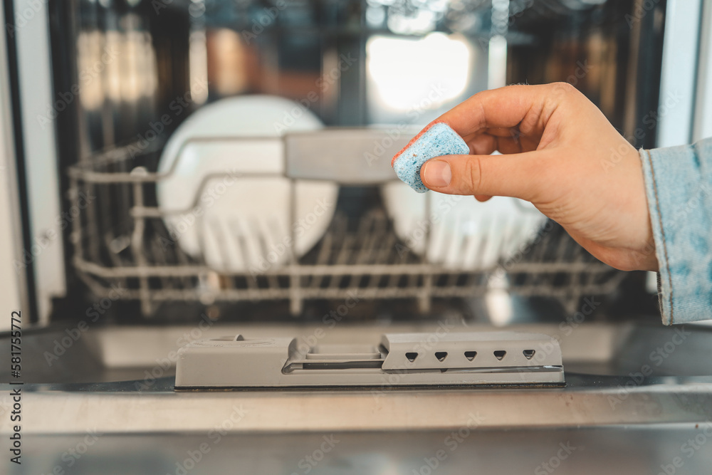 Dishwasher capsule, dishwasher tablets woman puts the capsule in the dishwasher Dishwasher capsule, dishwasher tablets woman puts the capsule in the dishwasher