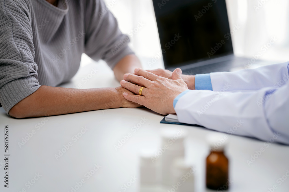 Male doctor holding hands to encourage senior patient and explai