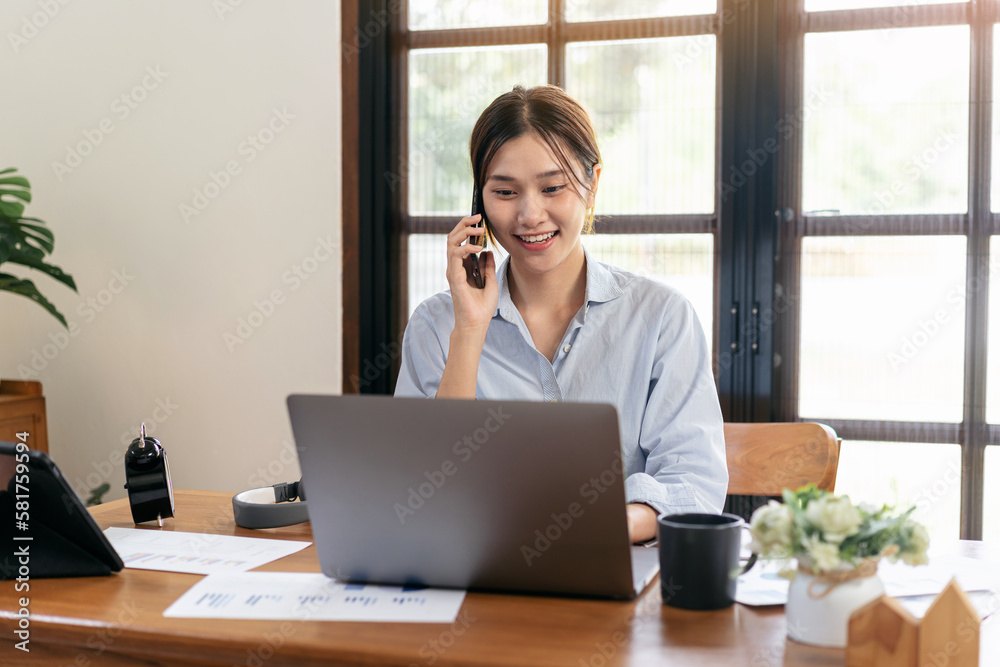 Female freelance is talking with colleague on smartphone and typ Female freelance is talking with colleague on smartphone and typ